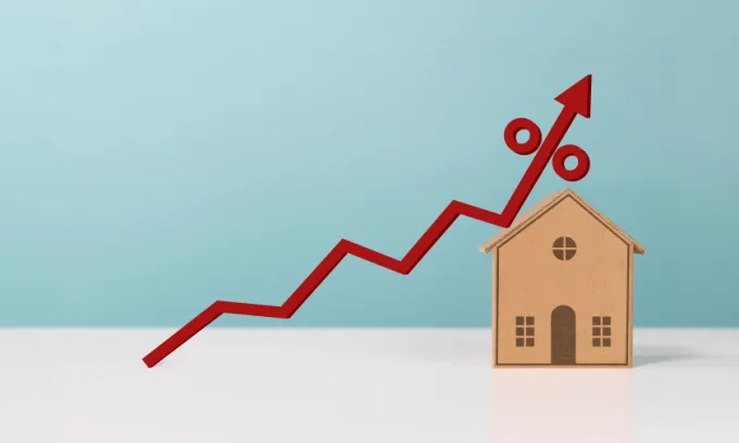 An image of a brown cardboard house with a red arrow pointing upwards 