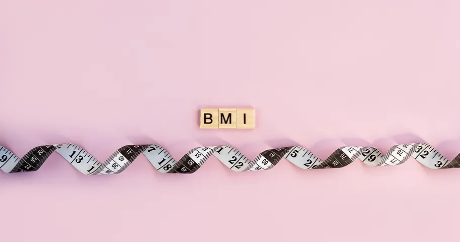Measuring tape and wooden blocks spelling the letters BMI.