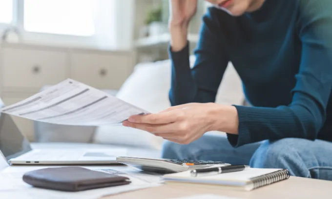 Young woman appearing stressed while looking at bills.
