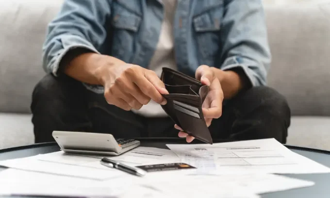 Young man opening empty wallet to find savings to buy a house.