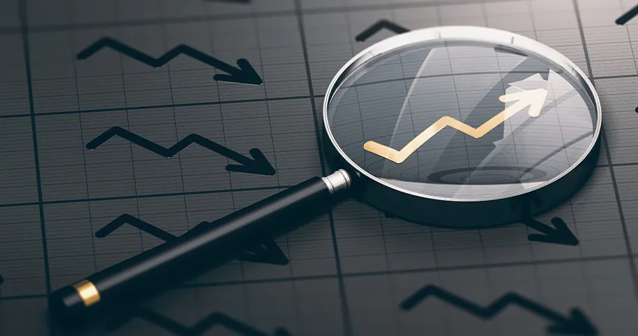 Magnifying glass highlighting climbing graph arrow alongside falling graph arrows.