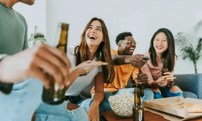 Friends hanging out with popcorn and beers, streaming a show on tv