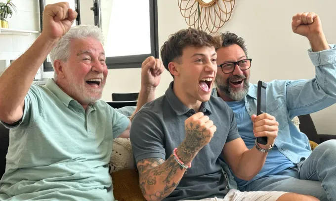 Three men streaming sports on the TV and cheering