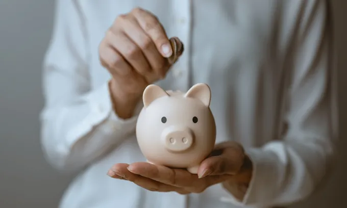 Person putting savings away in piggy bank
