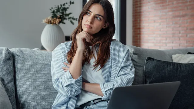 Worried young woman sitting on couch, distracted from work