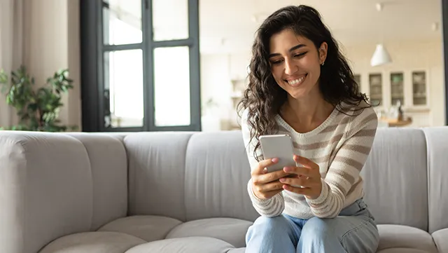 Women easily comparing different transaction accounts on her mobile phone while sitting at home.