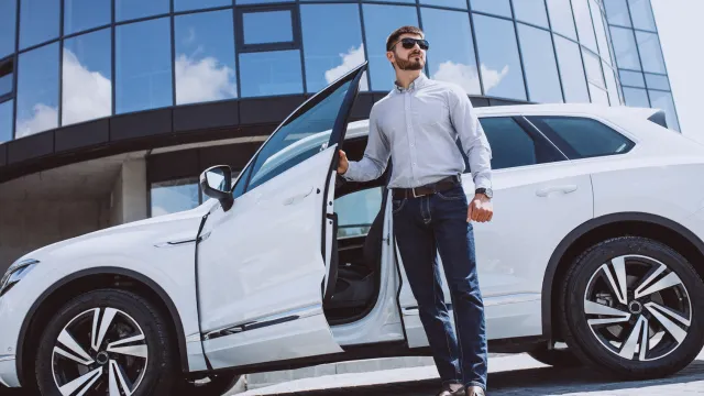 Business man stepping out of his white business car.