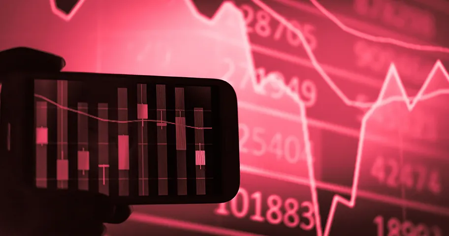 Mobile phone in front of a red graph of falling markets