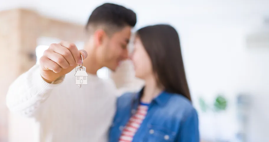 Young couple holding key to first home.