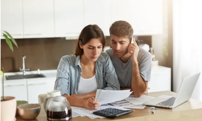 A young couple look over documents while on the phone