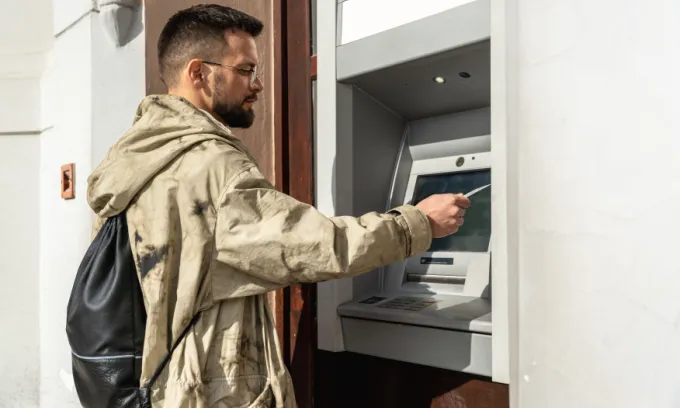 Man with short hair and a beard using a card at an atm