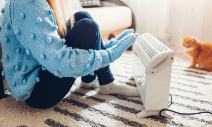 Woman using heater in Winter.