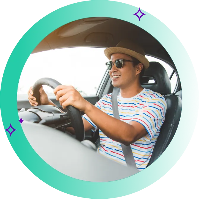 A man in sunglasses and a hat with his seatbelt fastened, happily driving behind the wheel.