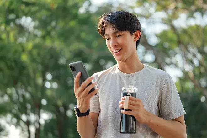 Man comparing policies on his phone while holding a water bottle