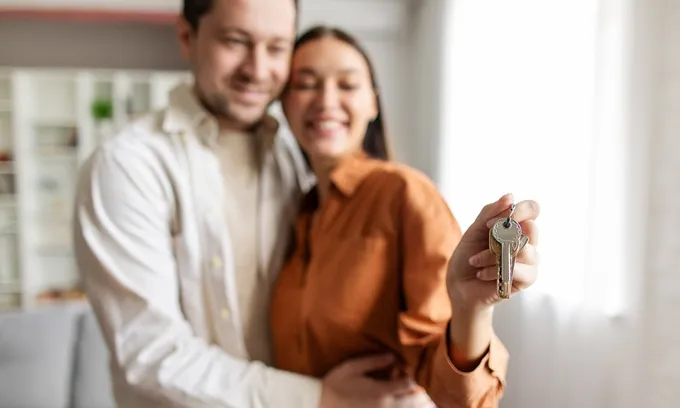 A young couple holding the keys to a dual key property, which can be an opportunity for a dual rental income.