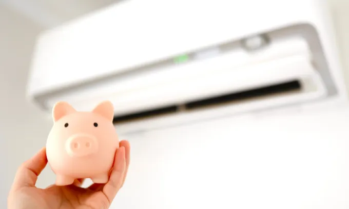 A close up of a piggy bank next to an air conditioning unit.