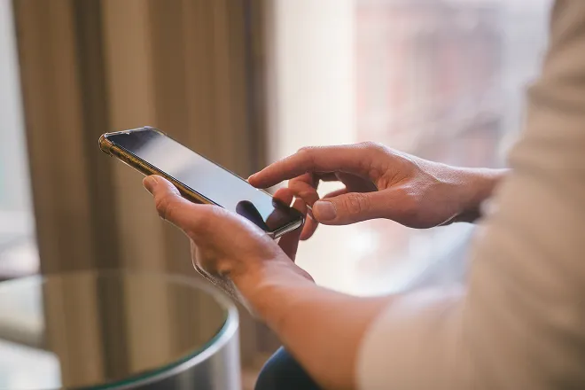 Person holding a phone and entering their mobile phone plan preferences