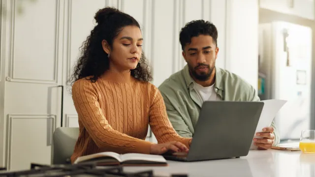 Couple researching ways to pay off mortgage faster on their laptop
