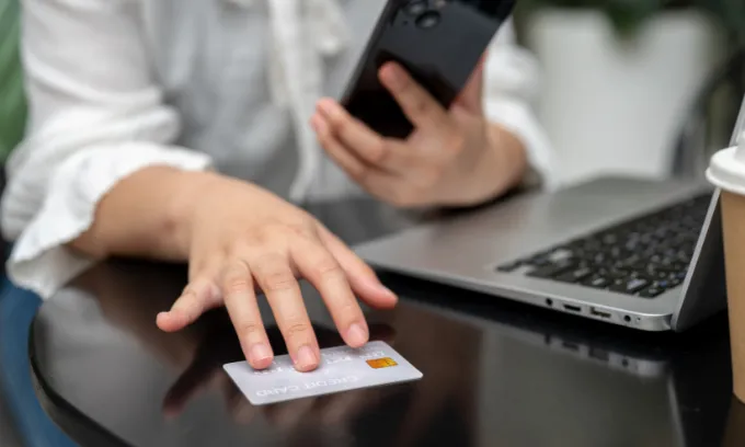 A woman holding a credit card and phone.