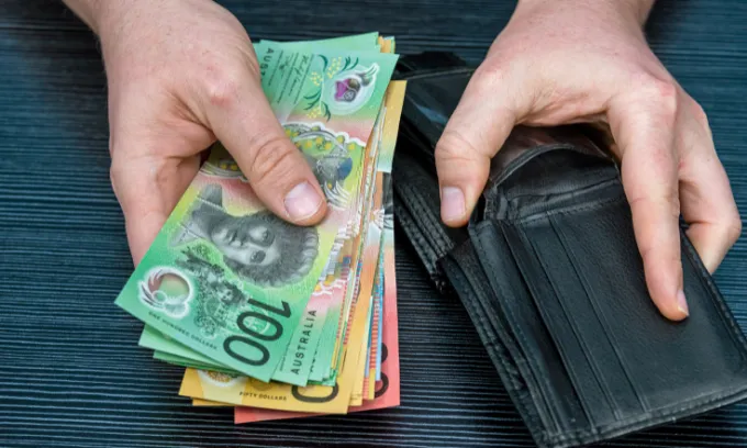 Man putting Australian bills into his wallet. 