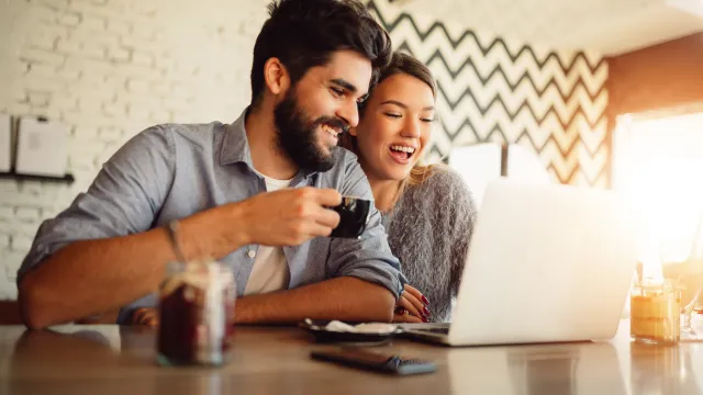 Happy couple surfing on a laptop after receiving their home loan pre-approval.