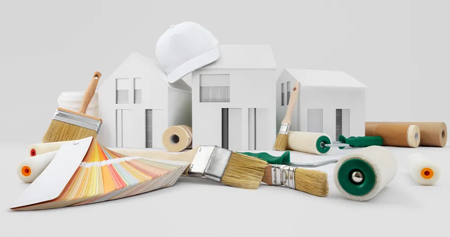 Paint brushes, rollers and colourful paint swatches against graphic of white model houses