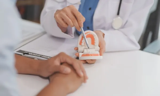 A dentist explains how dentures are used to a patient.