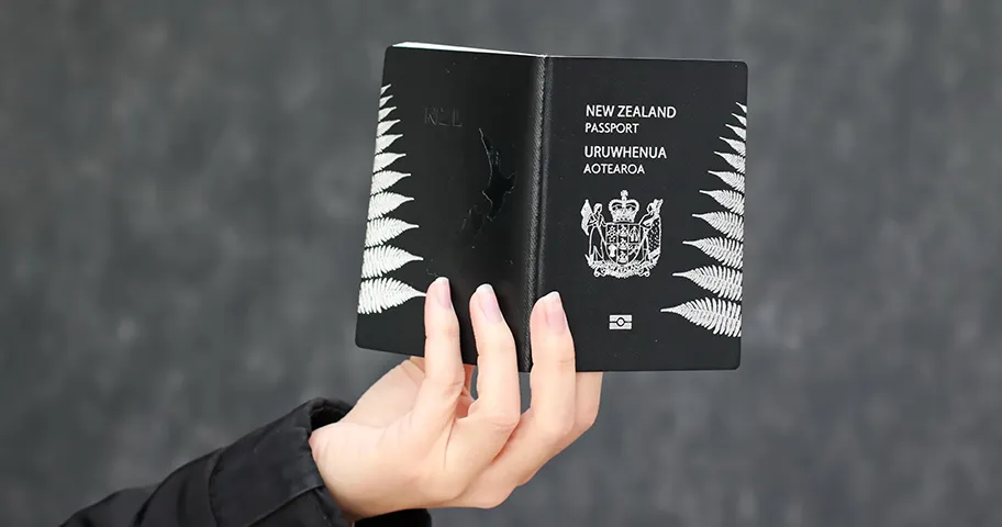 Female hand holding an NZ passport