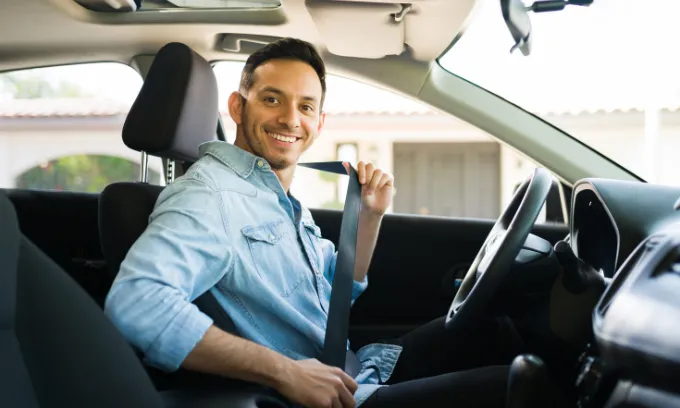 Portrait of a man driving away in a car he just bought.