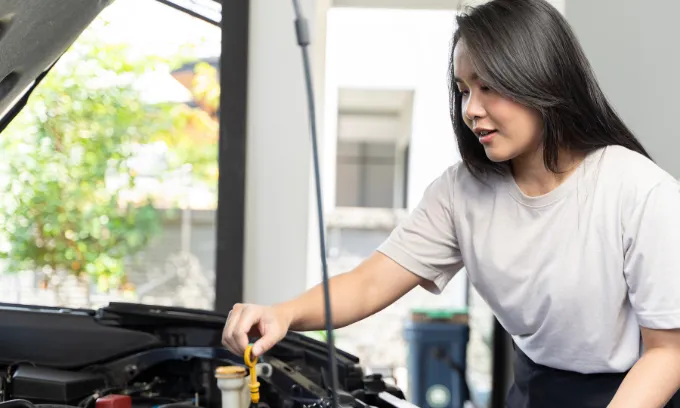 Woman checking her car engine by herself.
