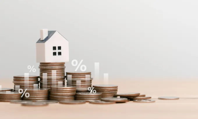An image of a house sitting on top of piles of coins with a bar chart and percentage signs overlaid