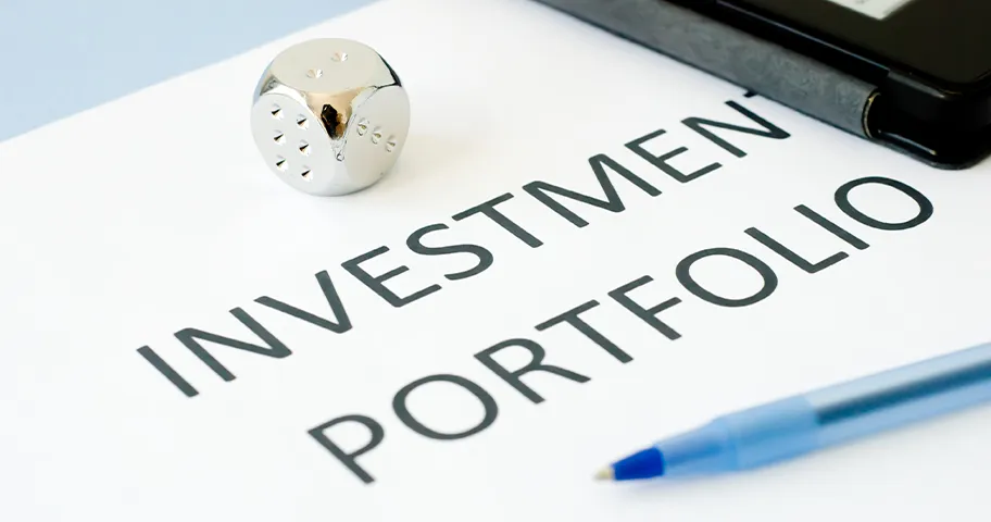 Paper with the words "Investment Portfolio" written on it with pen and silver die.