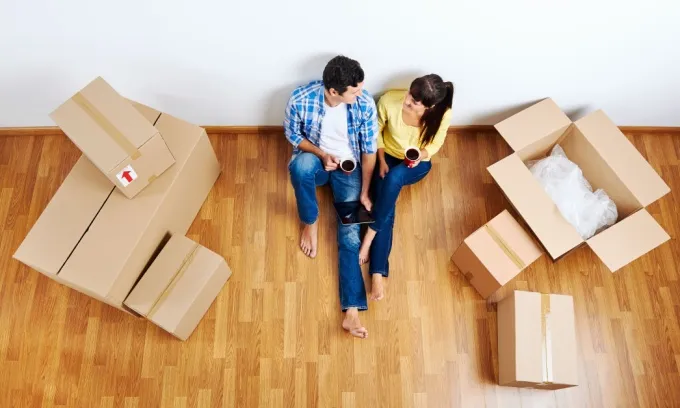 Couple sitting down next to moving boxes