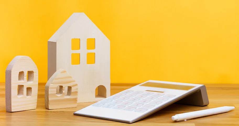 Calculator on table with wooden cut-outs of facades of houses
