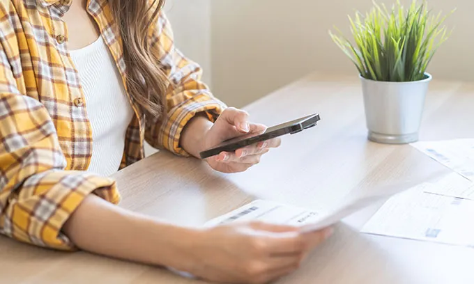Woman comparing bill ahead of mobile phone plan price rises in 2026