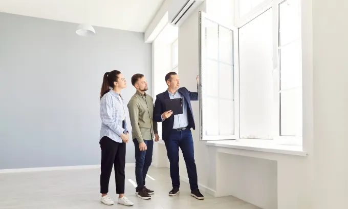 Young couple and agent inspect empty house.