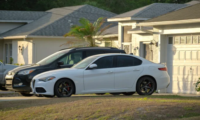Two cars parked on the driveway outside a house.