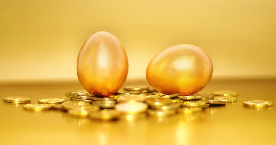 Two golden eggs and coins representing retirement savings