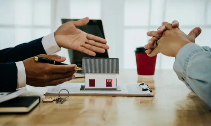 Two people shaking hands discussing buying a home. 