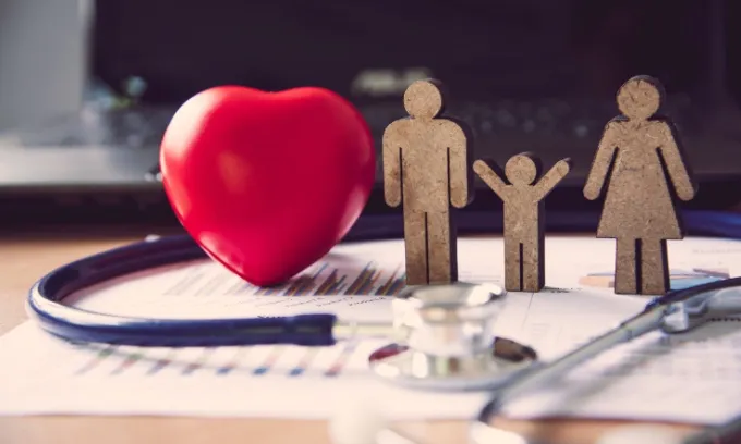 A wooden cut out of a family sit next to a red heart
