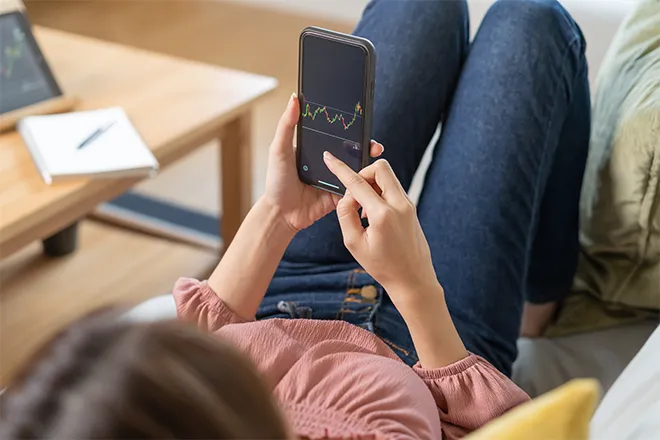 Reclining woman using share trading phone app