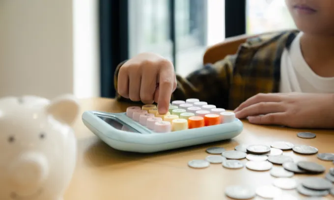 Young kid using calculator with money.