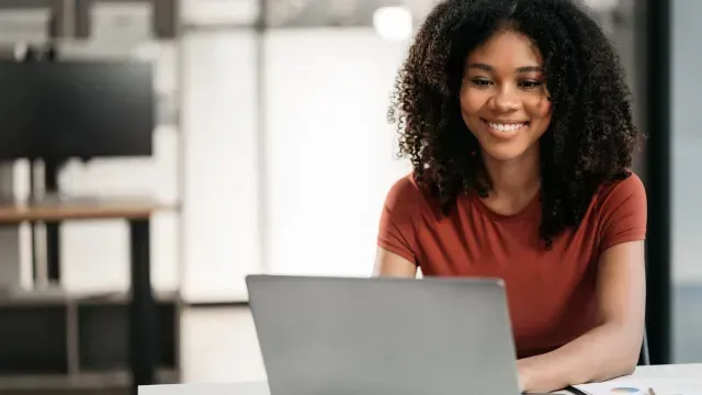 Woman smiling and comparing personal loans online on her laptop.
