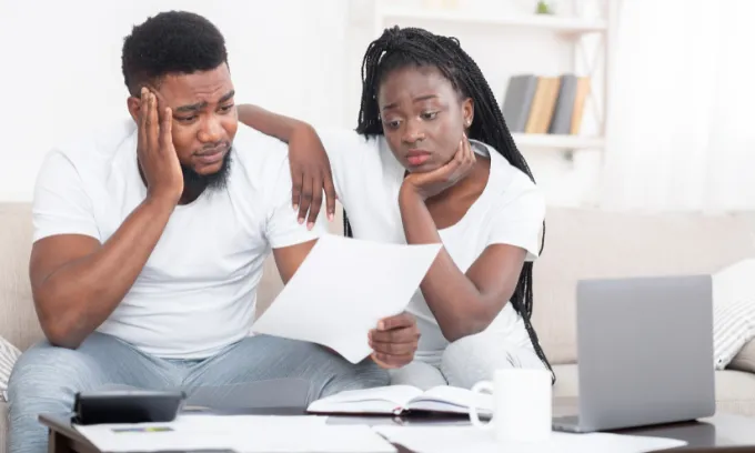 Couple looking at mortgage bill unhappily.