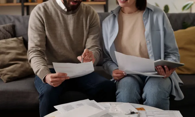 Cropped shot of young couple looking through text of financial document.