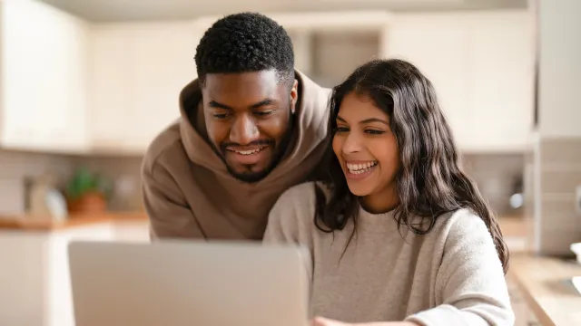 A young couple compares their refinancing options using a laptop.