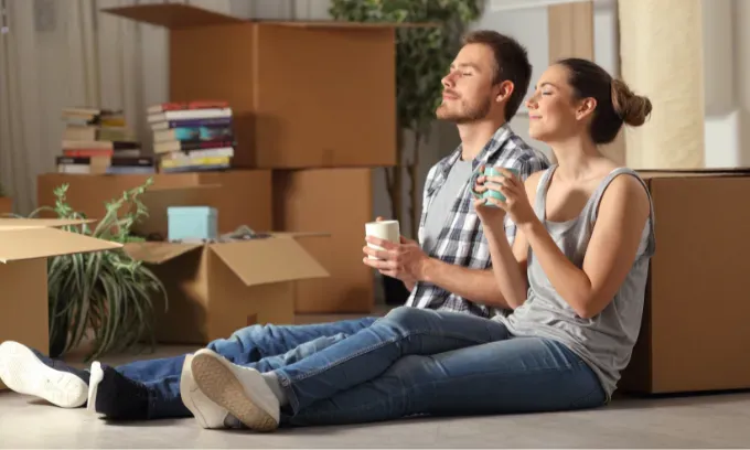 A young couple sitting with packed boxes, representing the title, ‘Renters insurance explained’.