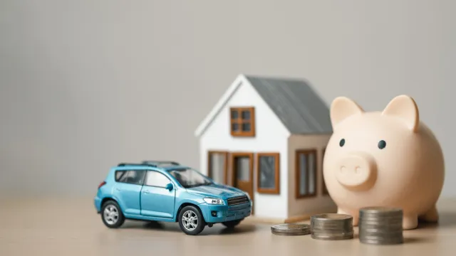 House, car, piggy bank and coins representing savings on car insurance