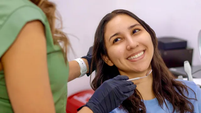 A smiling woman listens to her dentist.