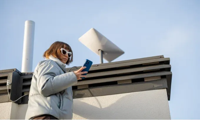 Person looks at phone near satellite